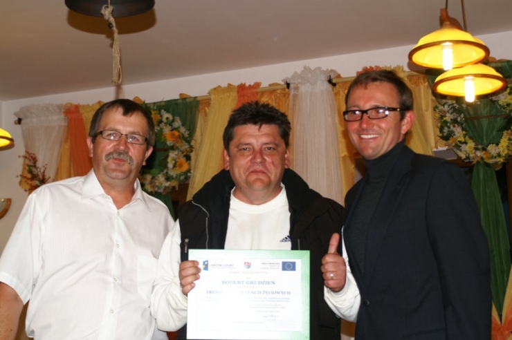Pan Marcin Lewiński wraz z Julianem Włodarczykiem wręczają dyplom uczestnikowi szkolenia 1 z 2