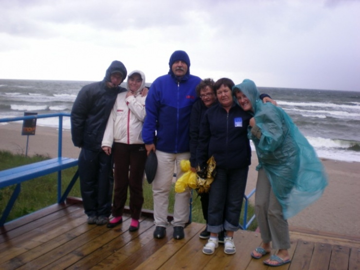 Mokry dzień, uczestnicy w płaszczach przeciw deszczowych nad plażą